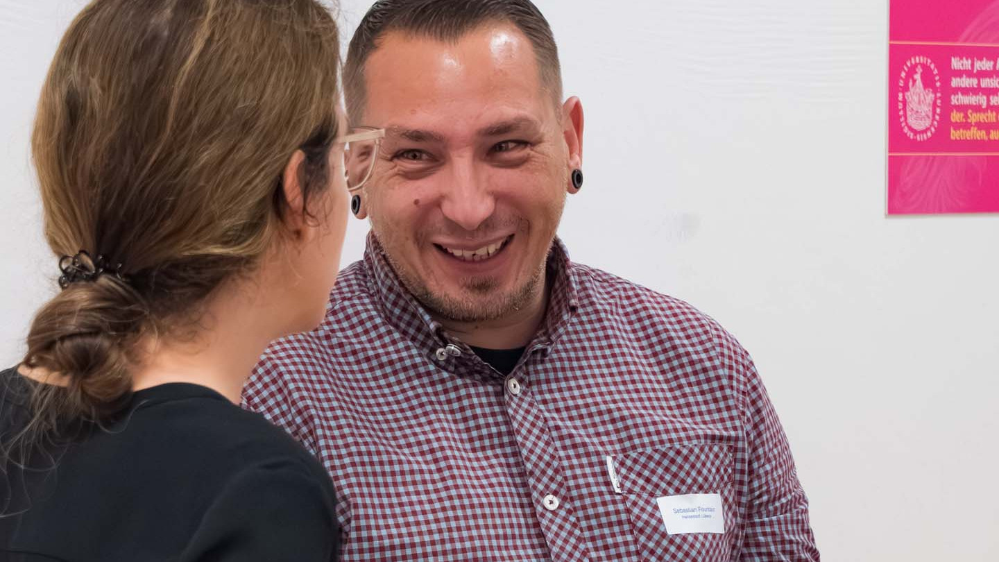 Ein Mann lacht im Gespräch mit einer Frau